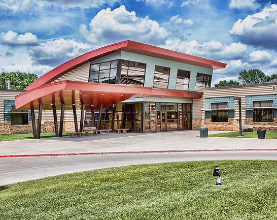 A large building with a red roof surrounded by a lush green grassy area.
