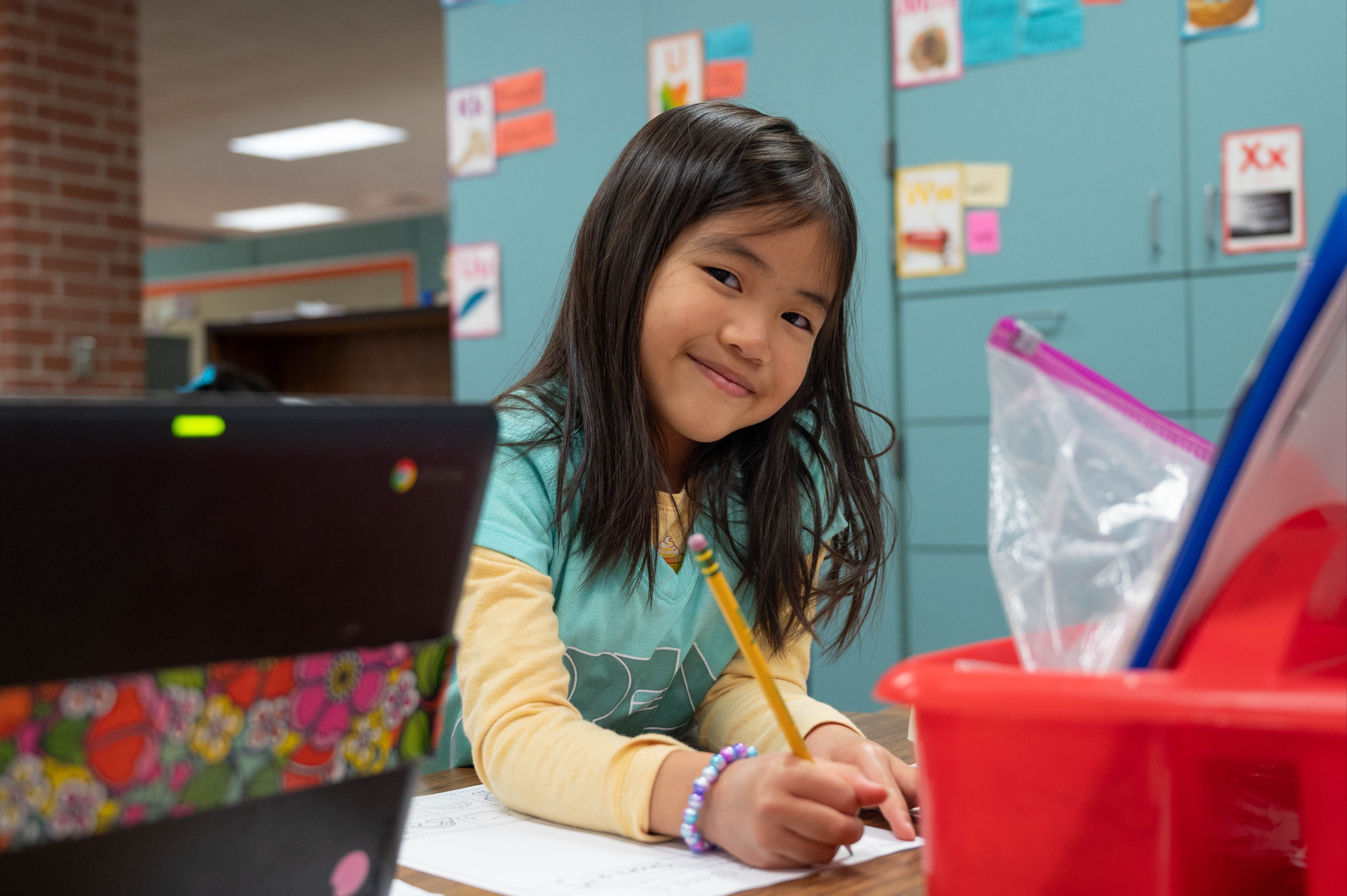 Student smiling at camera while writing