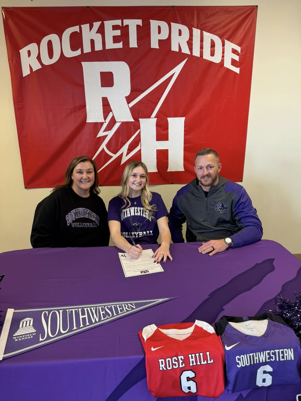 Kadence signs her paperwork with her parents nearby.