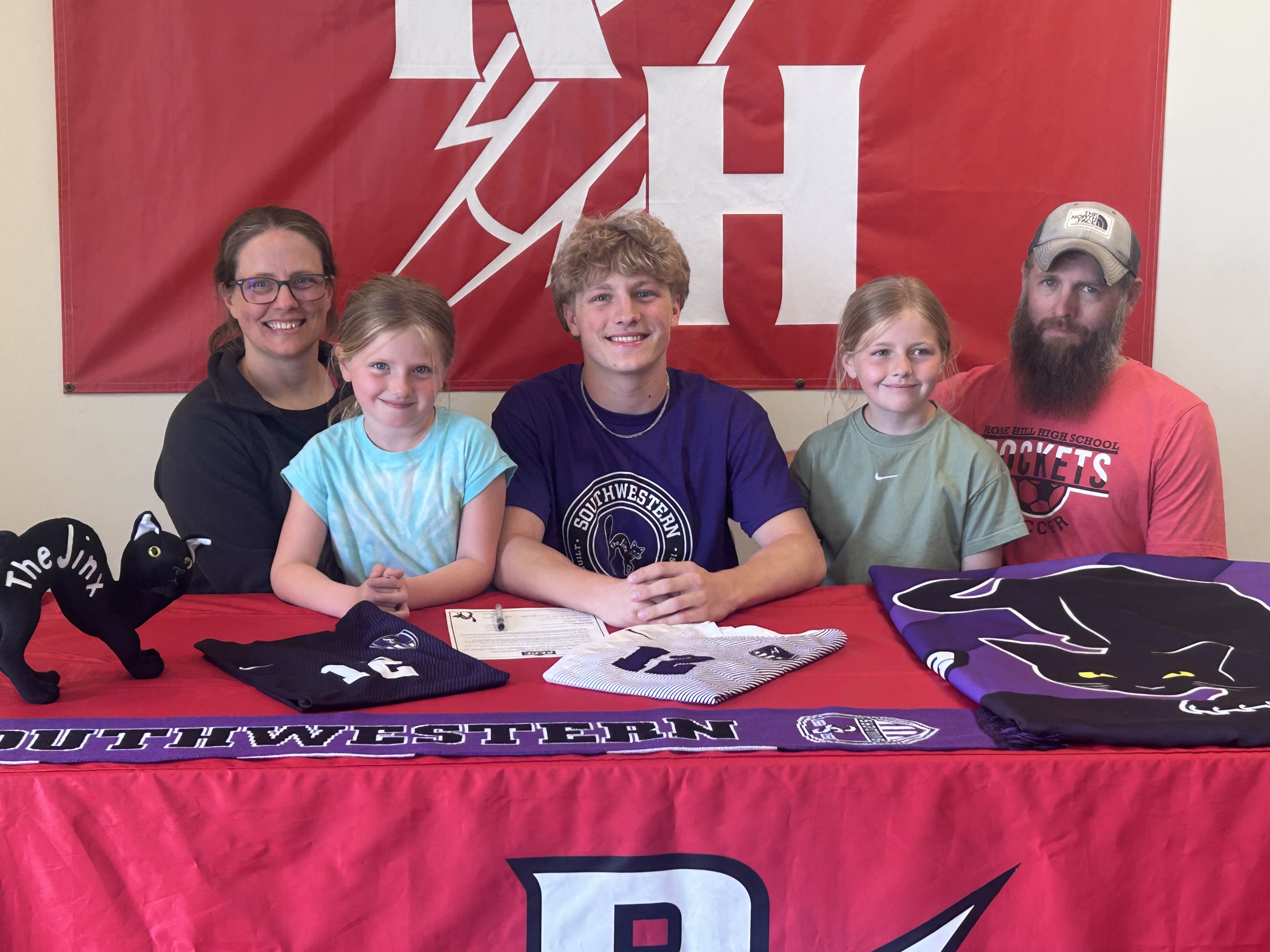 Cooper signs his paper surrounded by his family.