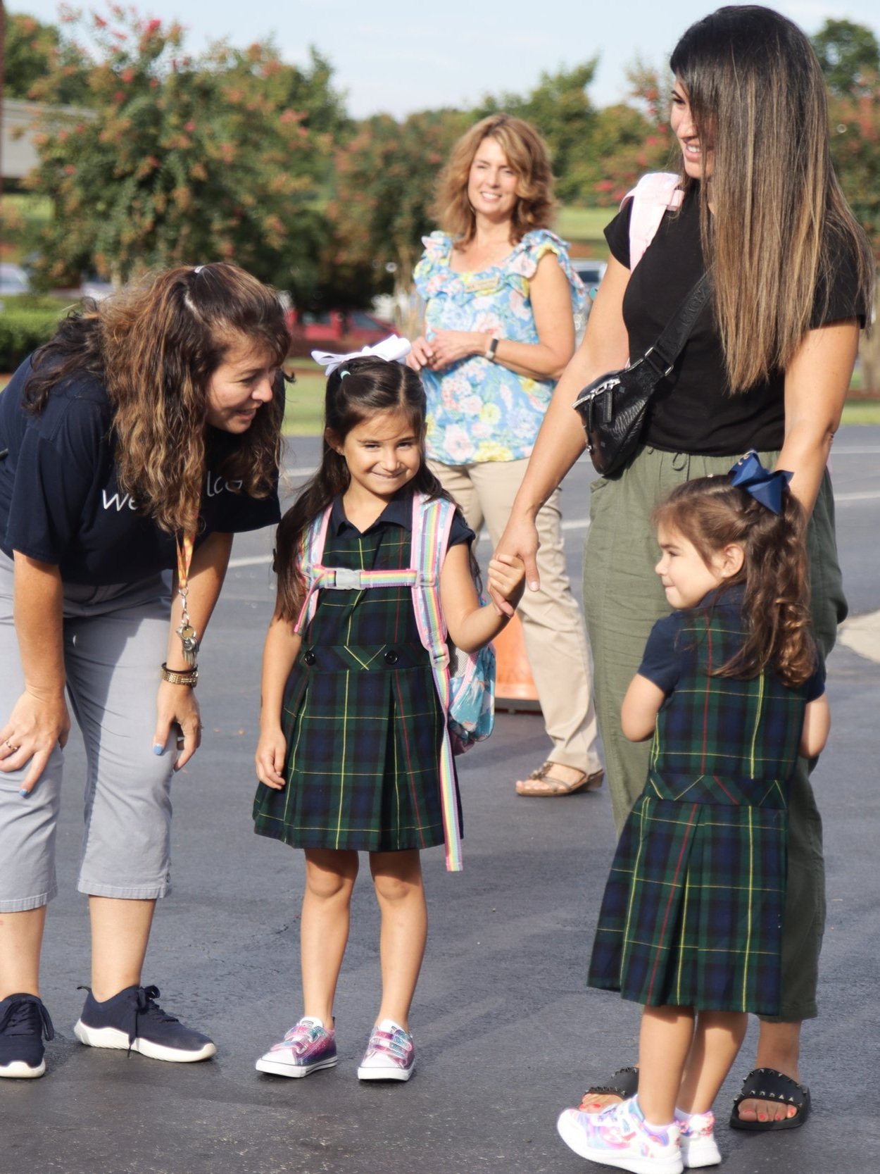 A teacher talking to two girls and a mom
