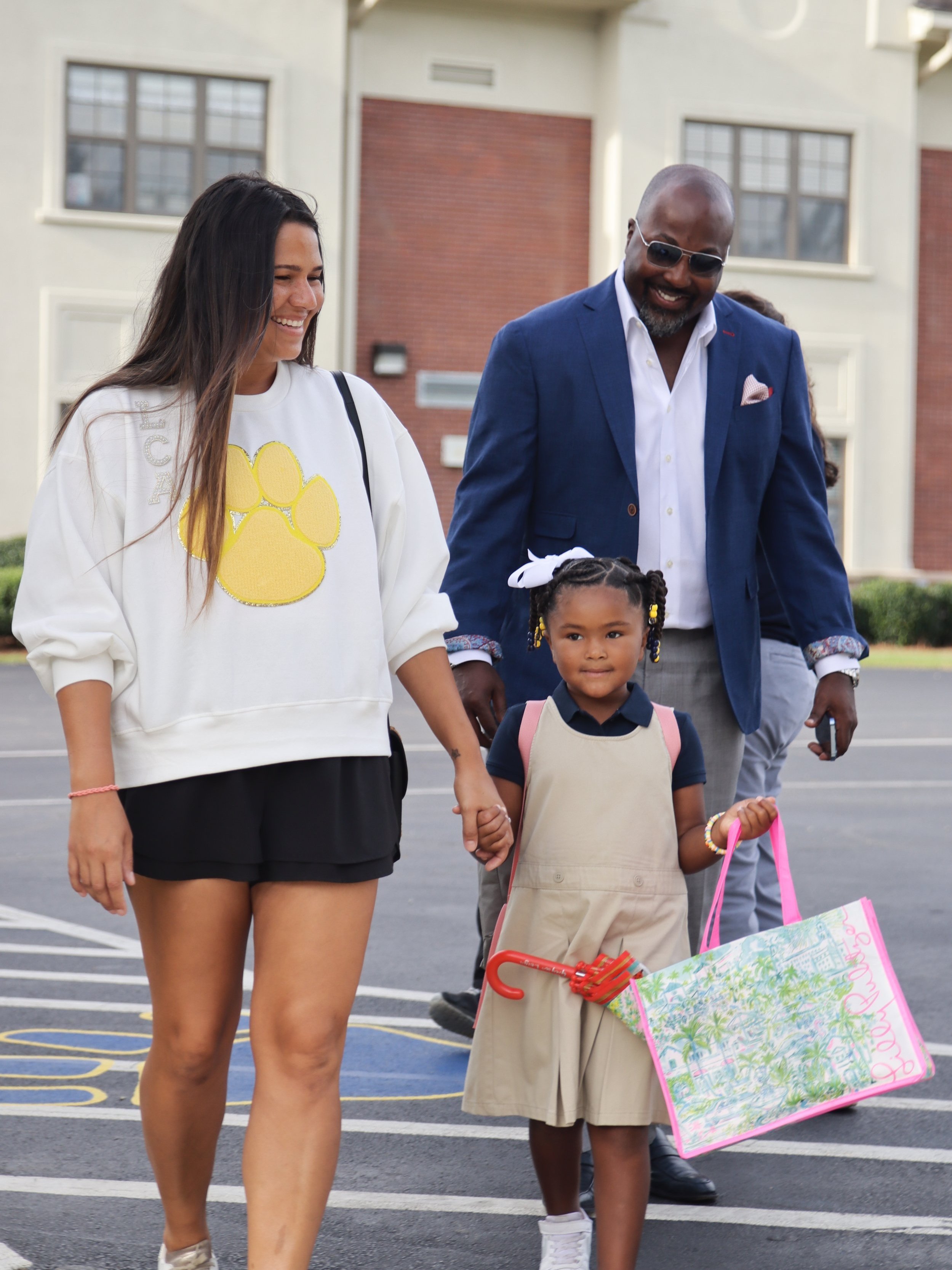 A mom and dad walking their daughter into school