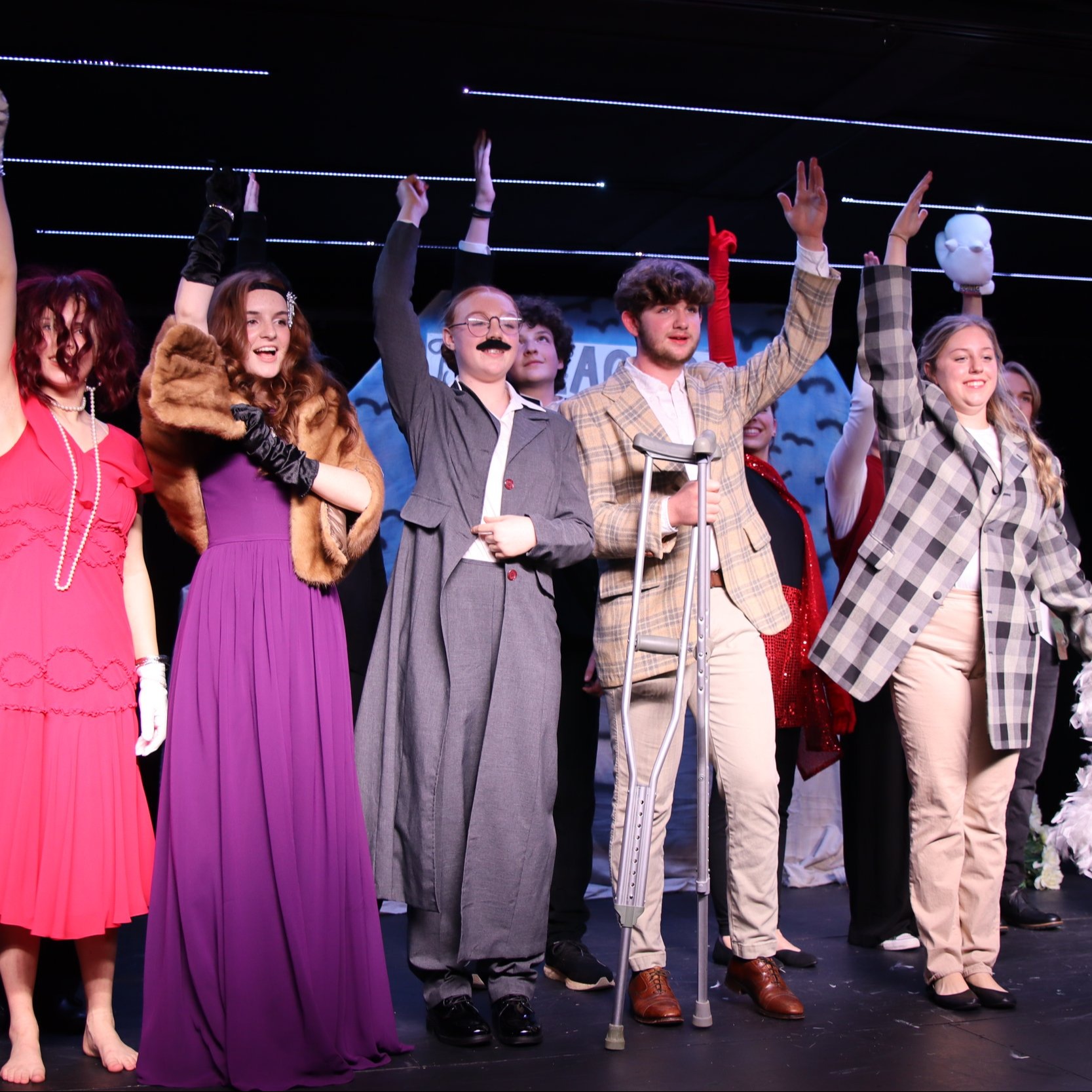 theatre students standing on stage and raising one hand