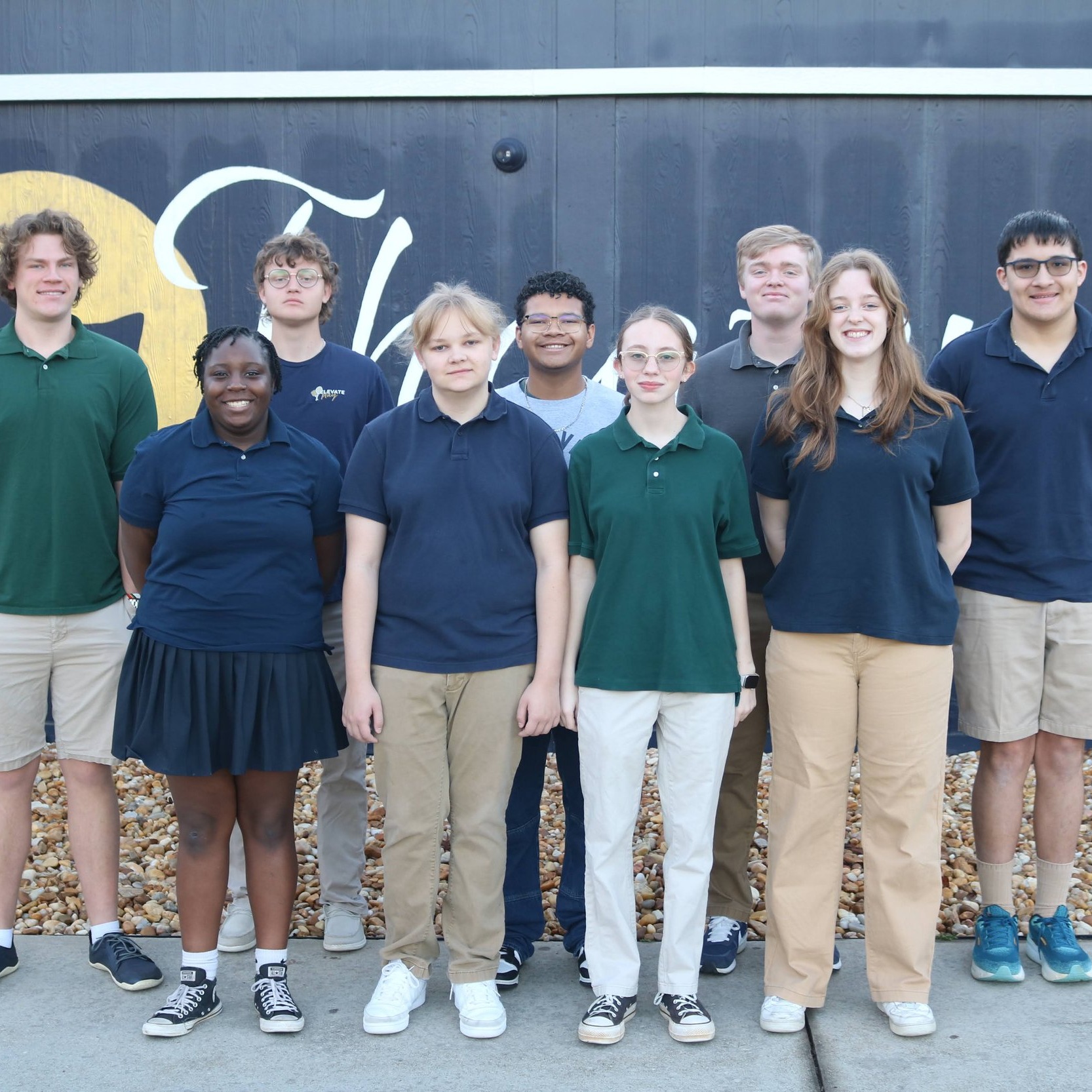 students standing outside of fine arts building and smiling