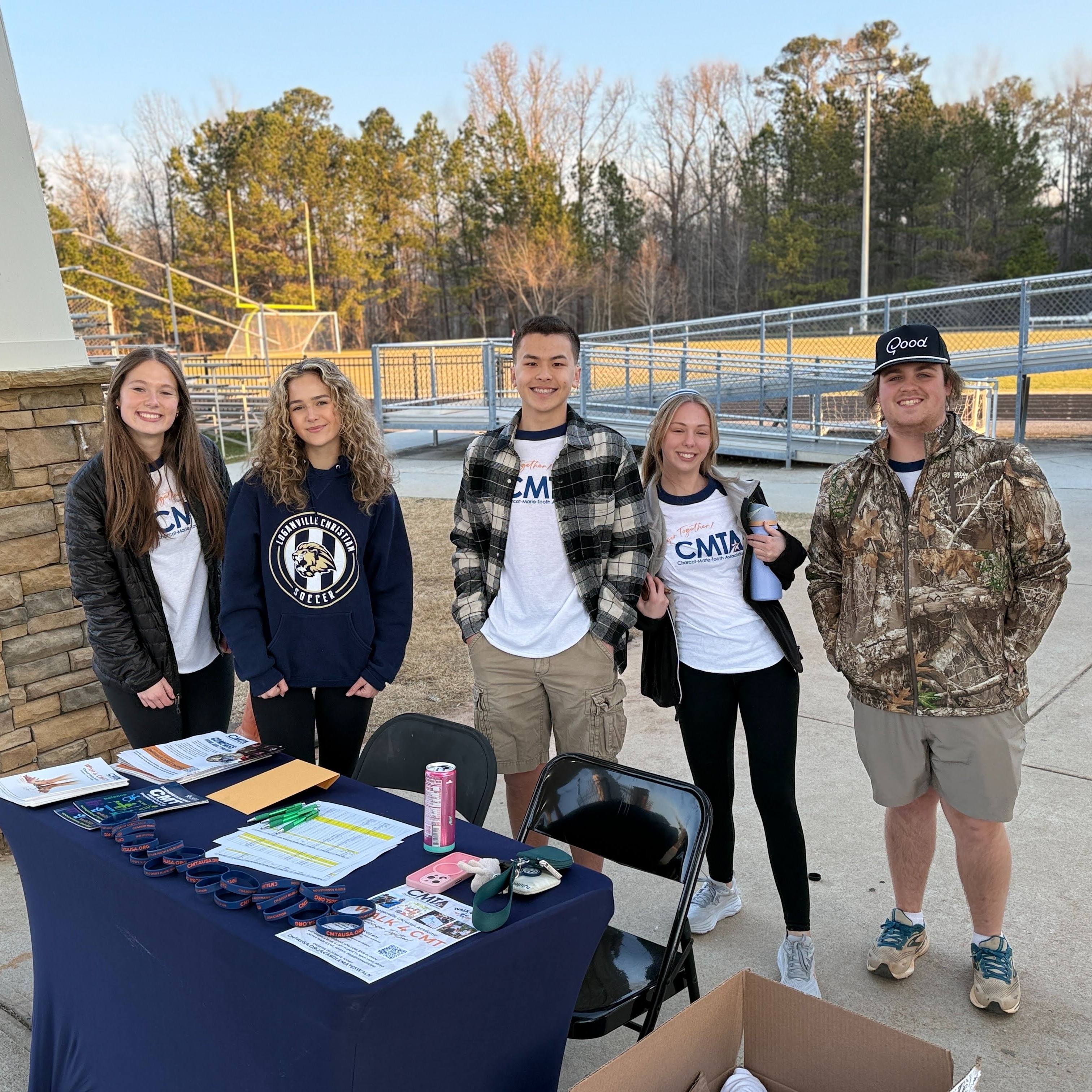 5 students standing behind a table and smiling