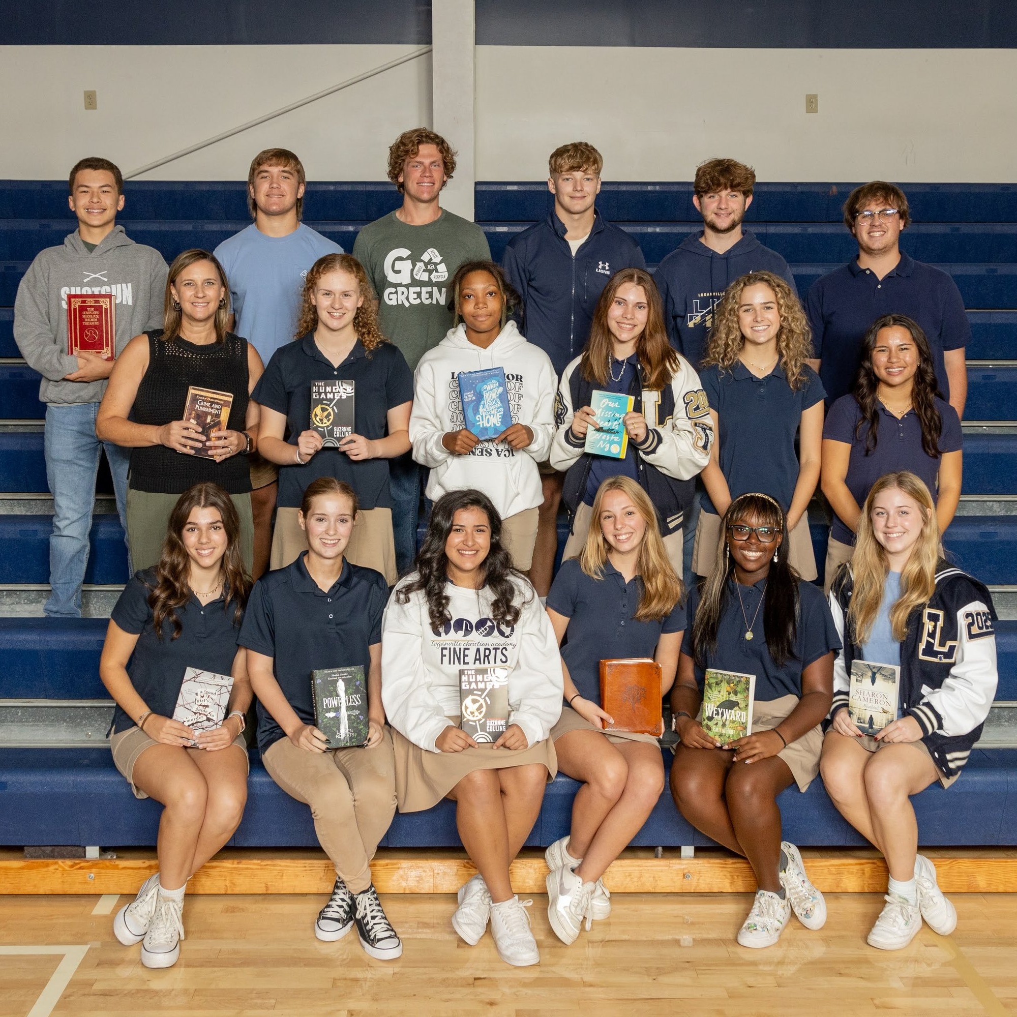 group of students sitting on bleachers, holding books, and smiling
