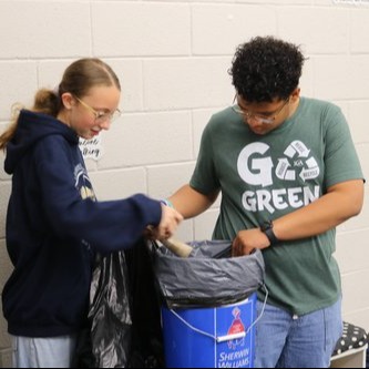 2 students sorting through trash and recycling