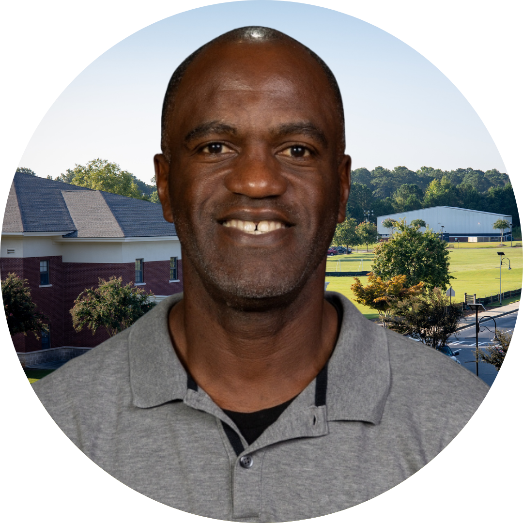 A smiling man in front of a school building