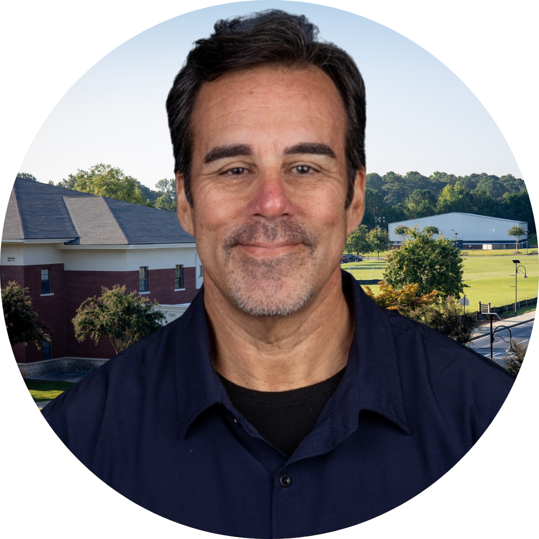 A smiling man in front of a school building
