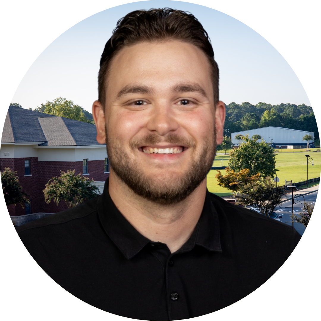 A smiling man in front of a school building