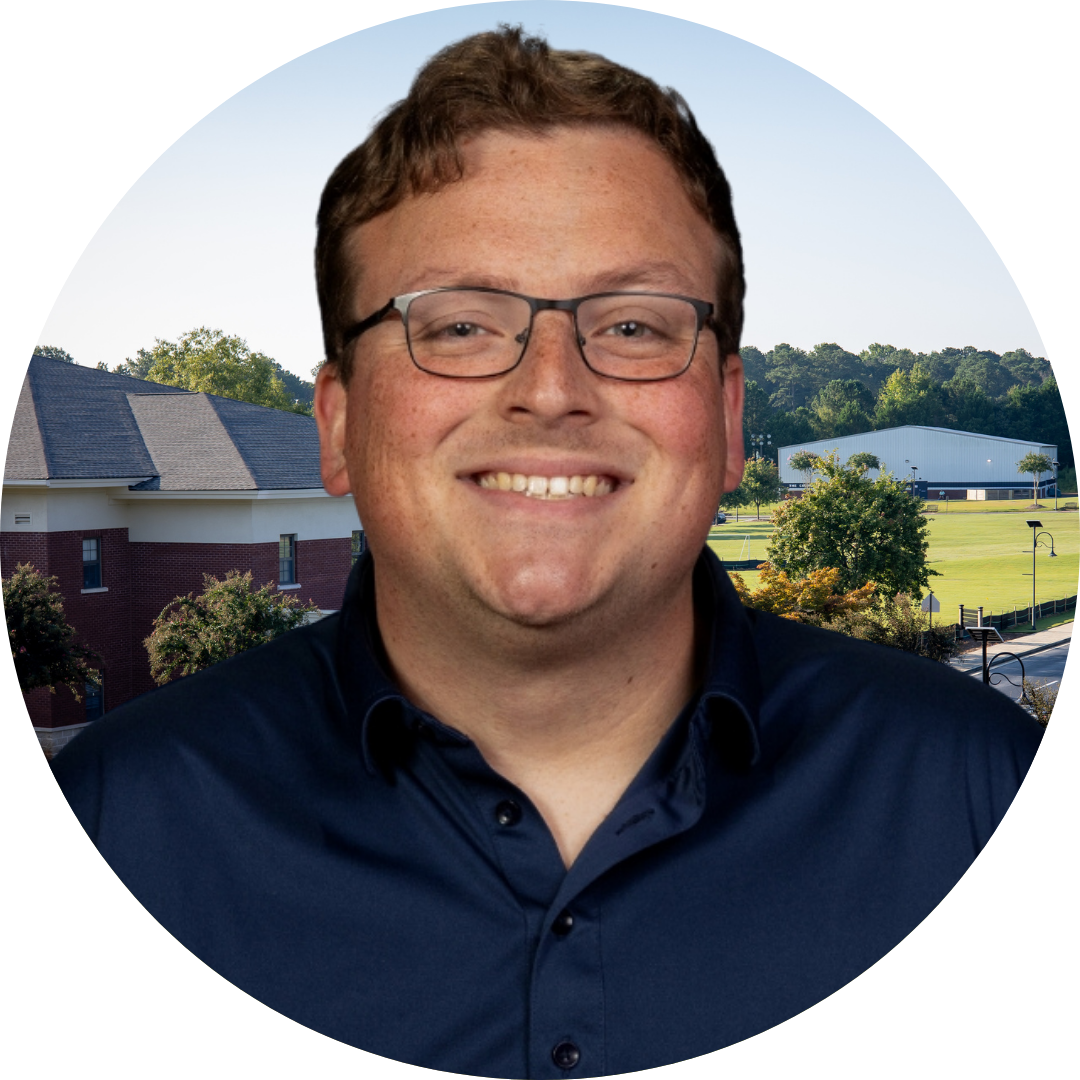 A smiling man in front of a school building