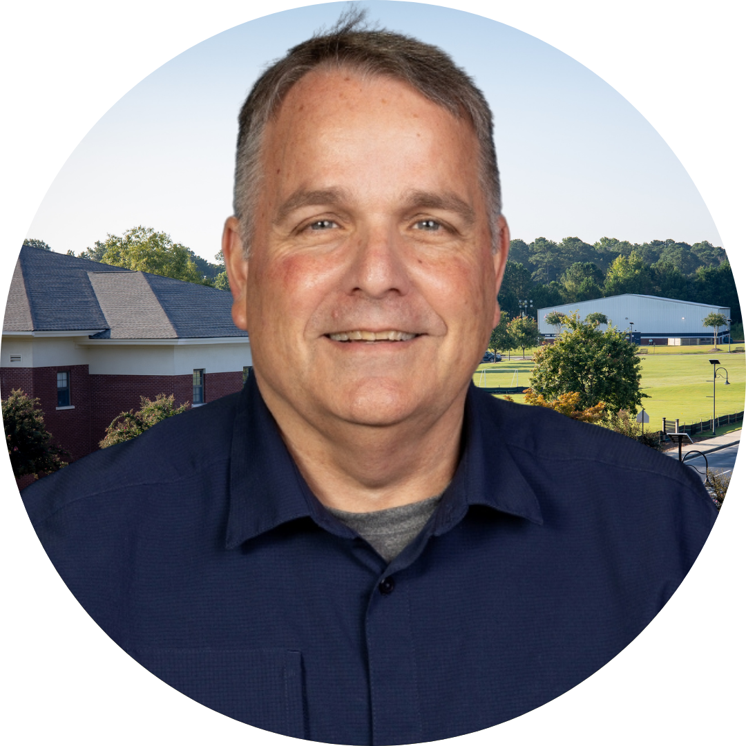 A smiling man in front of a school building