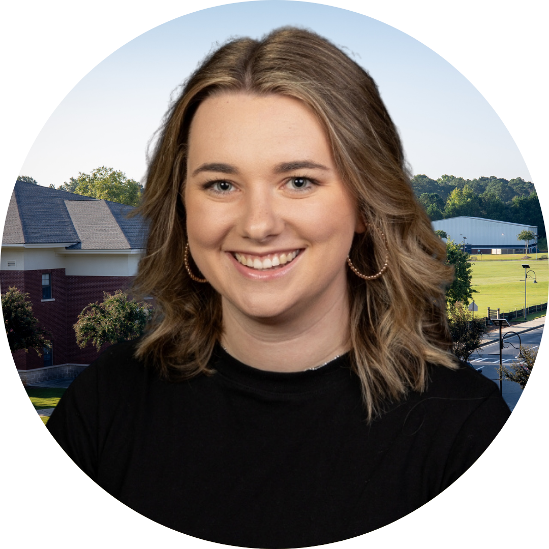 A smiling woman in front of a school building