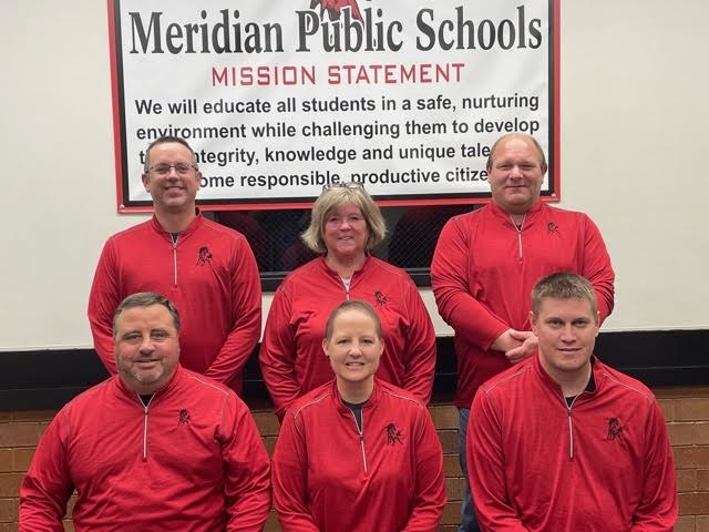 A group photo of the Meridian Public Schools staff, smiling and standing together in front of the school building.