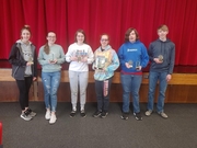 Six students proudly display their awards, smiling and standing together in a celebratory pose.