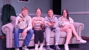 Four young people sitting together on a couch in a cozy room, engaged in conversation and enjoying each other's company.