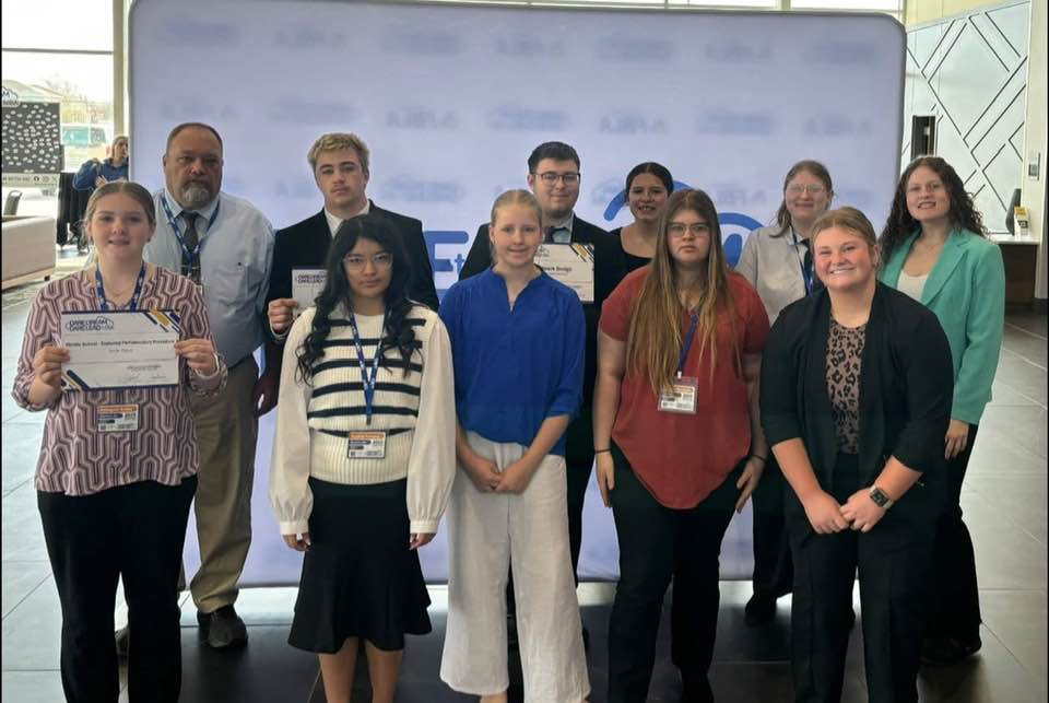 A diverse group of individuals proudly holding certificates in front of a celebratory banner.