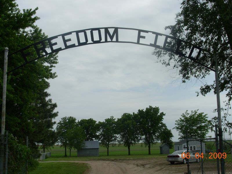  Entrance to Freedom Field, a former concentration camp in the United States, marked by a solemn sign and surrounding landscape.