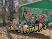 A group of children joyfully sitting on a colorful butterfly sculpture in a park setting.
