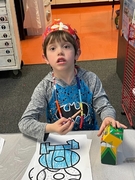 A boy wearing a pirate hat sits at a table, focused on creating a paper craft project.