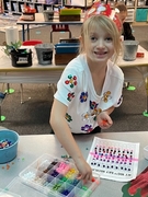 A young girl smiles while engaged in crafting activities, surrounded by colorful materials and tools.