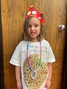 A young girl smiles while wearing a shirt featuring a large cookie graphic.