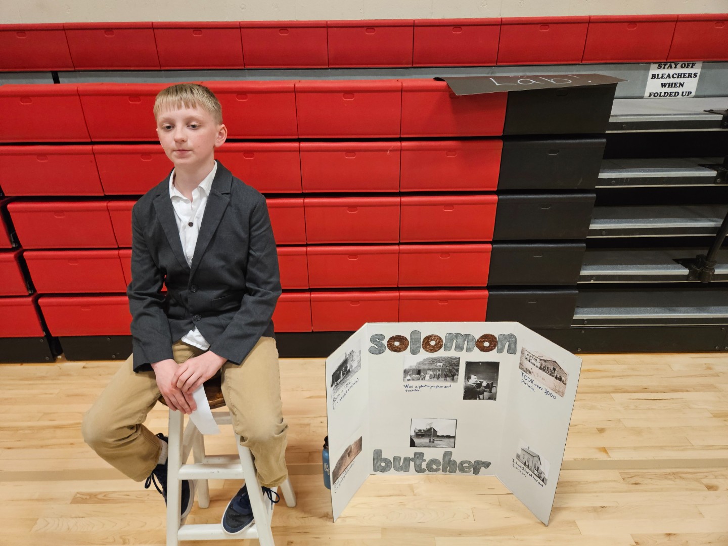 A boy sitting on a stool, looking at a colorful display of items in front of him.