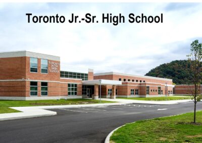 A view of Toronto Jr.-Sr. High School, showcasing its brick exterior and surrounding landscape with a cloudy sky above.