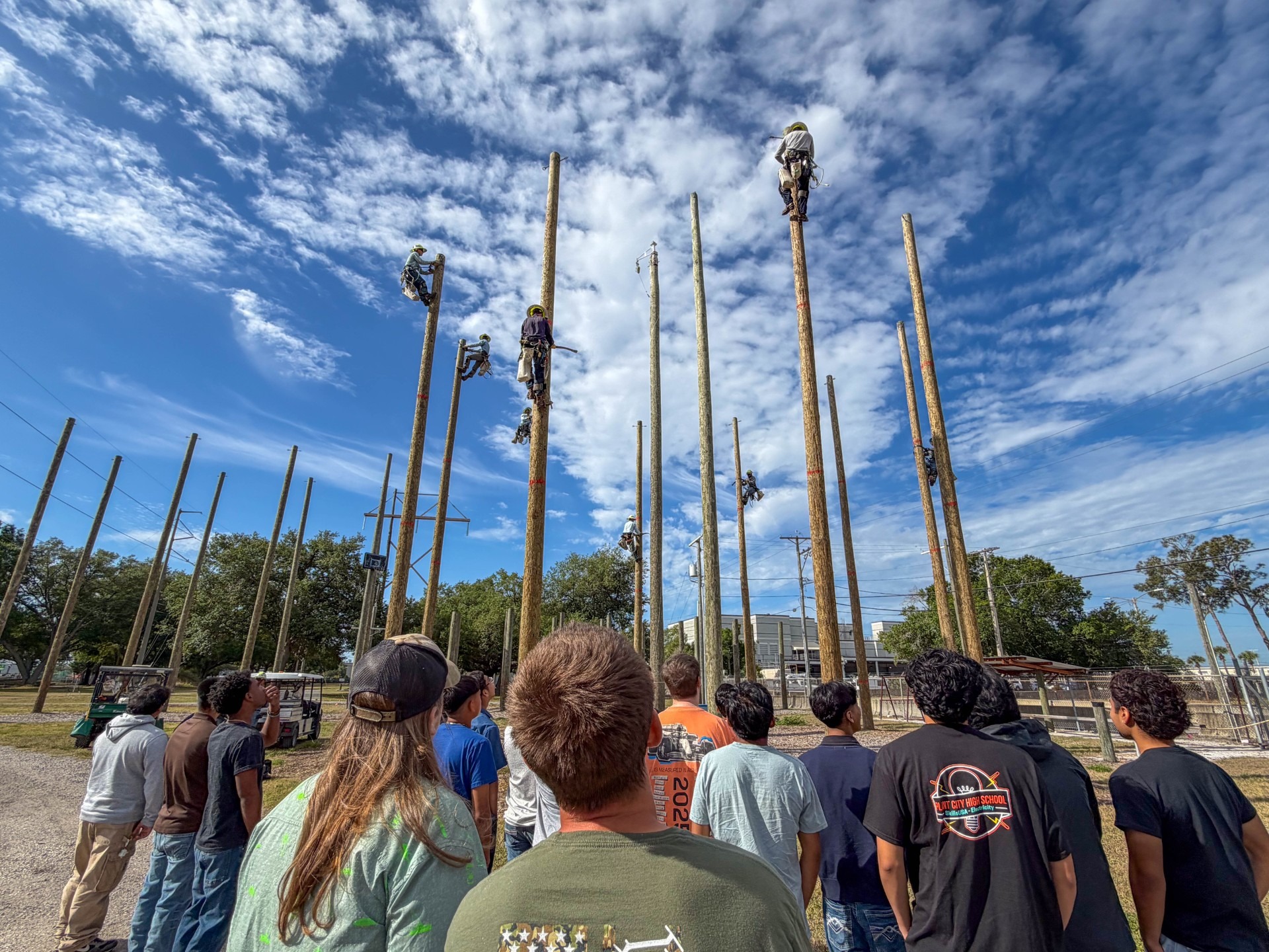 students watching workers work on electricity poles
