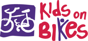 A colorful logo featuring the text 'Kids on Bikes' in bold red letters, accompanied by a simple illustration of a bicycle in a purple square background.