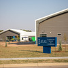 A modern building complex with a blue sign in front, featuring a playground area and landscaped grounds.