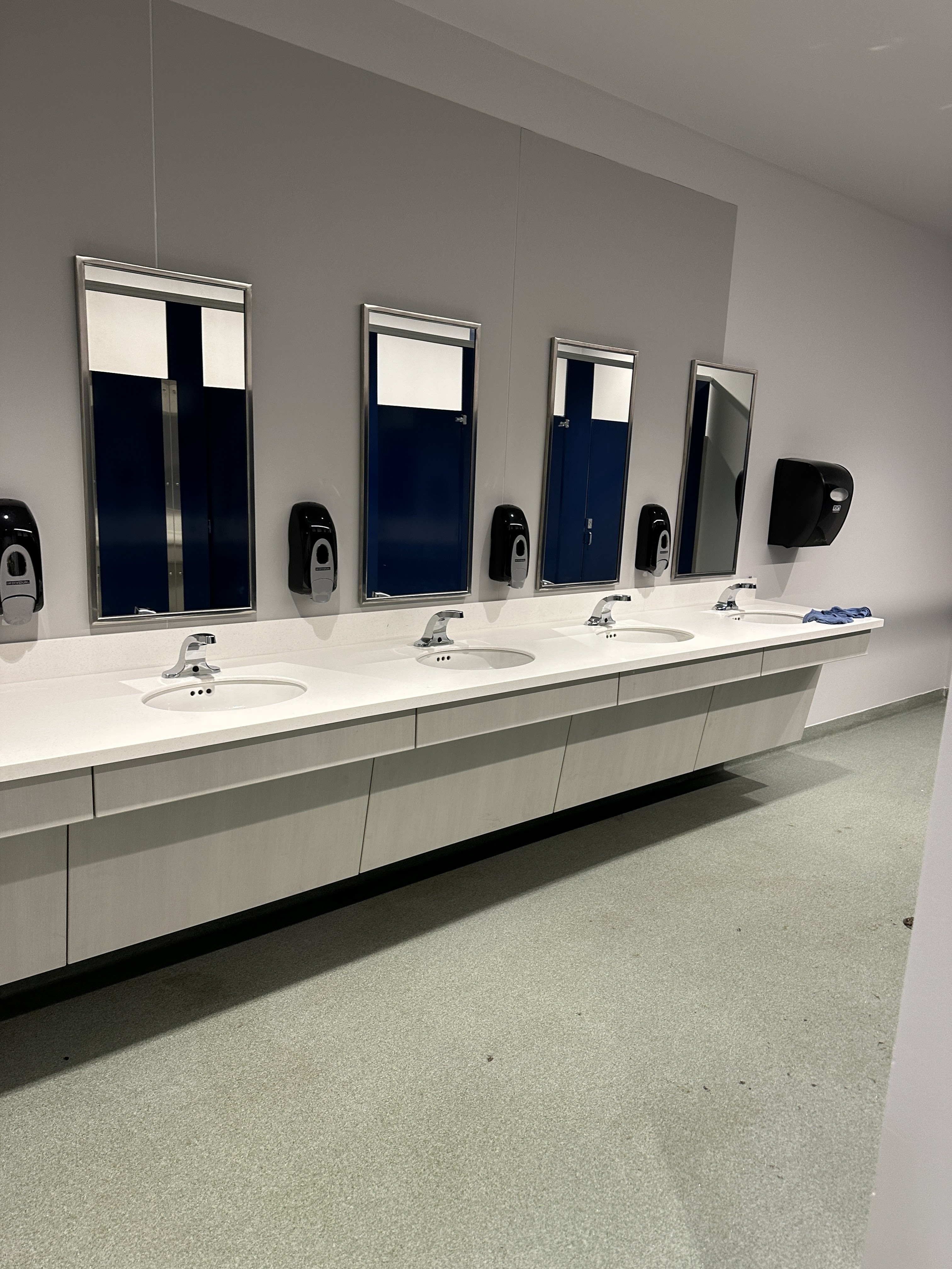 A clean public restroom featuring multiple sinks and mirrors, with soap dispensers mounted on the wall.