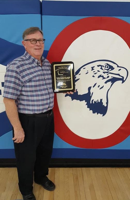 person holding a plaque in front of school mascot 