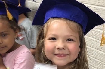 Young girl in Airport graduation cap smiles