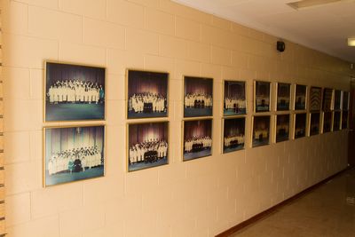 A hallway displaying a series of framed photographs arranged in two rows, featuring groups of people in formal attire, likely from various events or ceremonies.