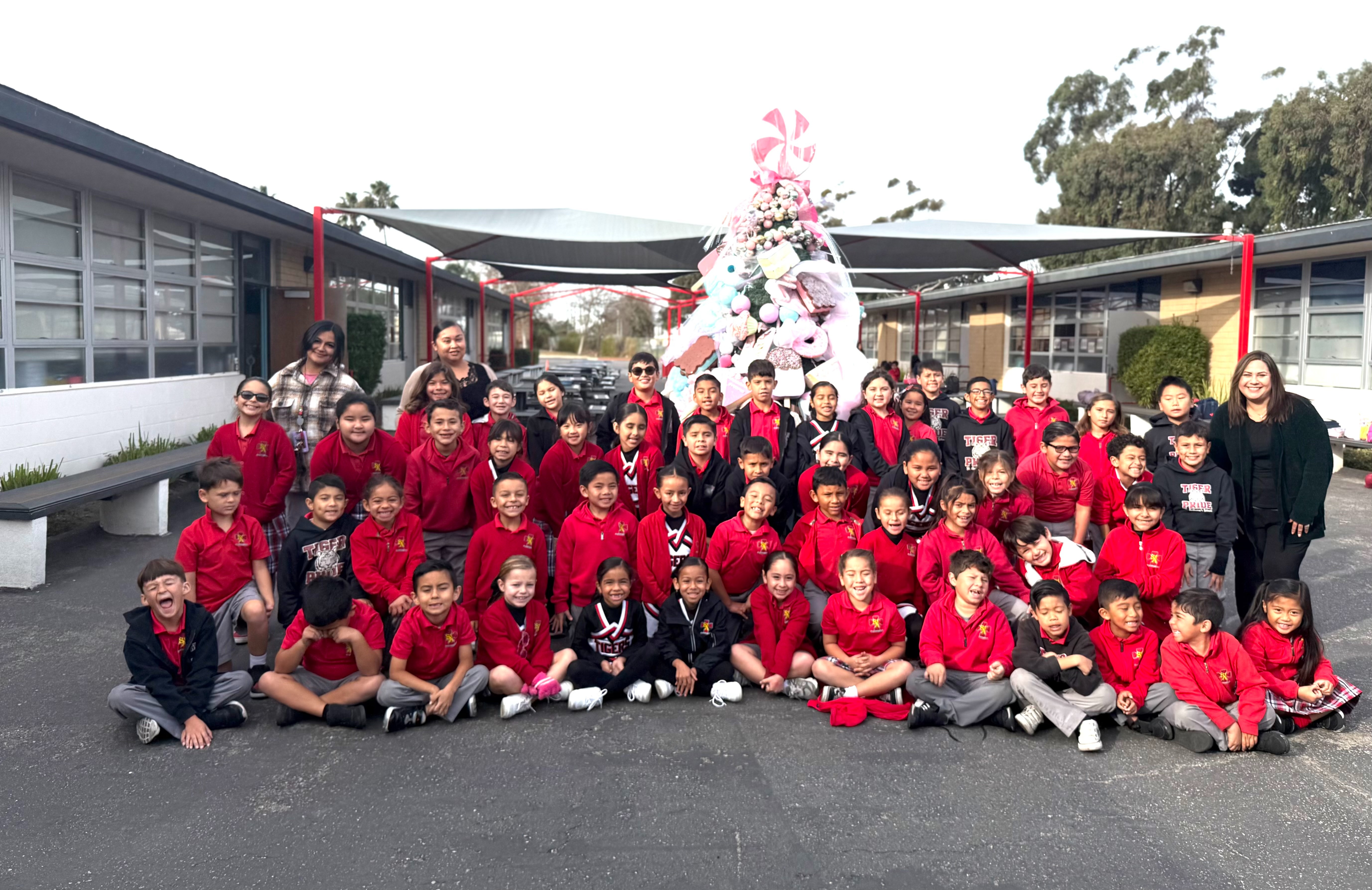 Four students stand in front of a wooden altar with a crucifix, dressed in school uniforms, with their hands clasped in prayer.