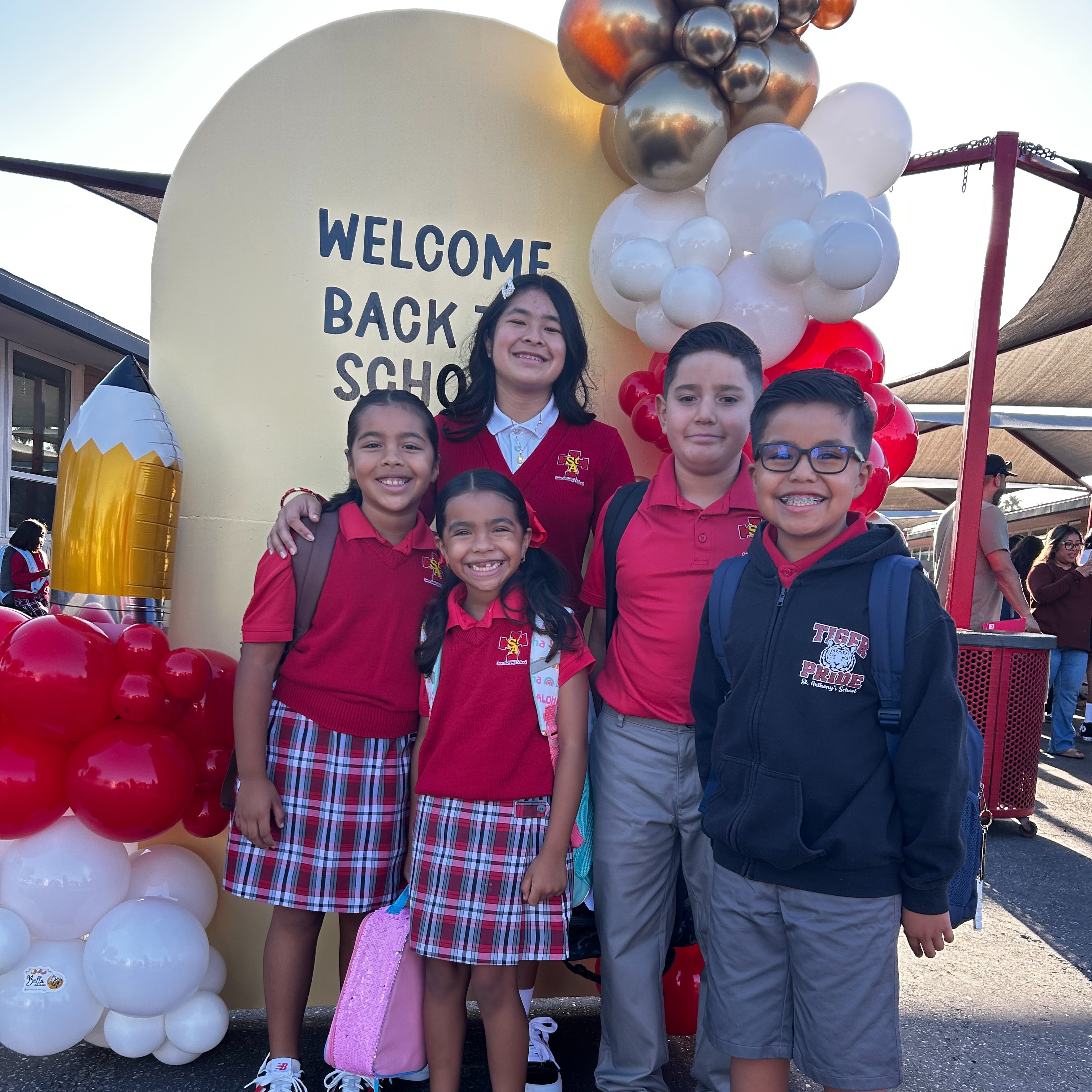 Two young children are seated at a table, focused on coloring small drawings, with various art supplies visible around them.
