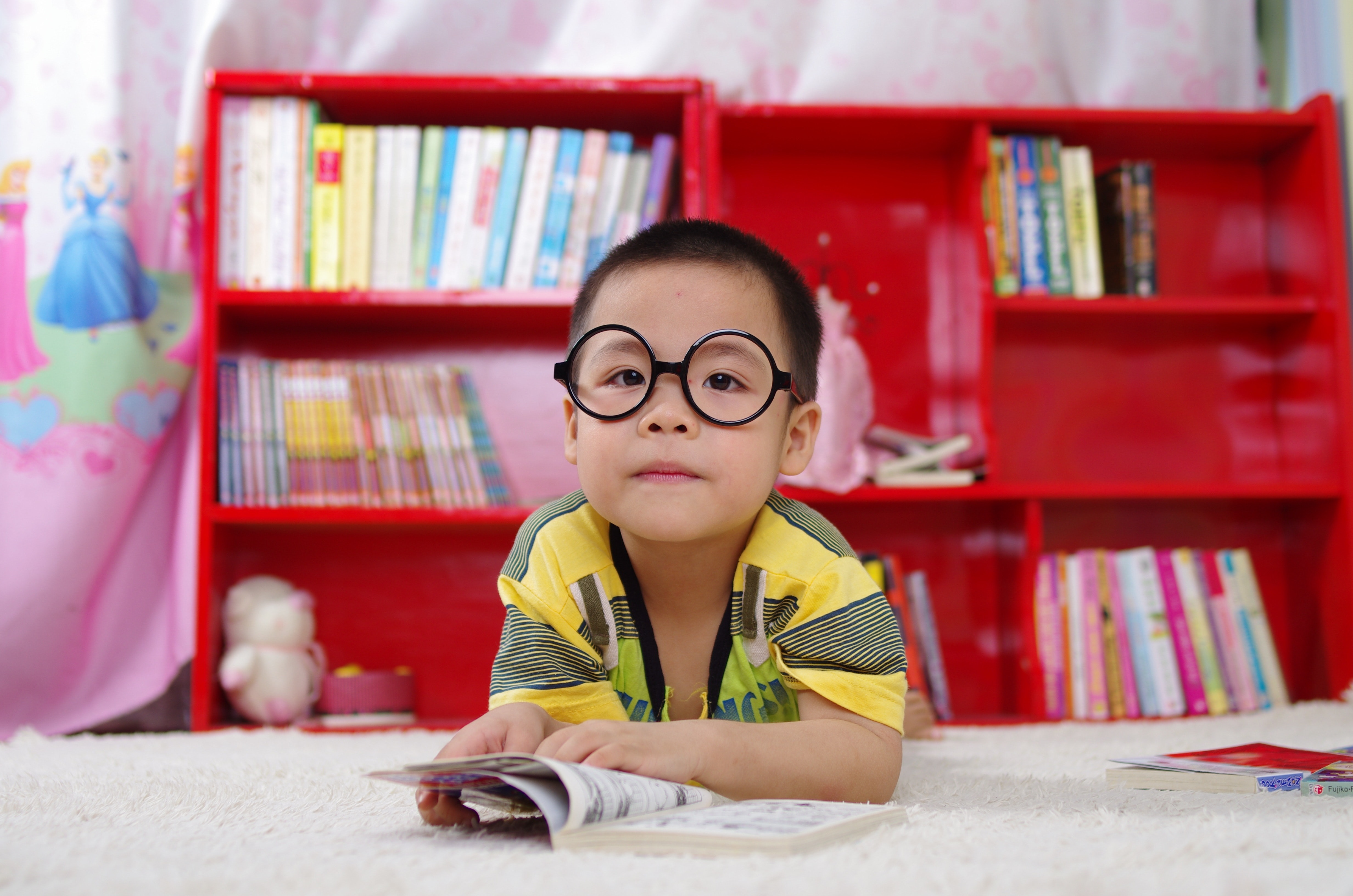 student with book kneeling in front of bookcase 