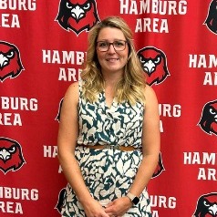 Amanda Gallagher smiling with a hamburg hawks media wall in the background.