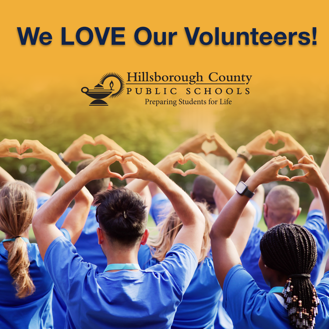 We love our volunteers. A group of adults with the backs to the camera holding up hearts made with their hands