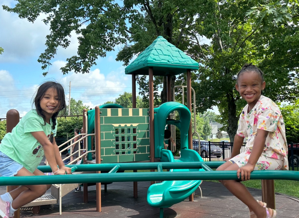 Two students on the playground, smiling at the camera.