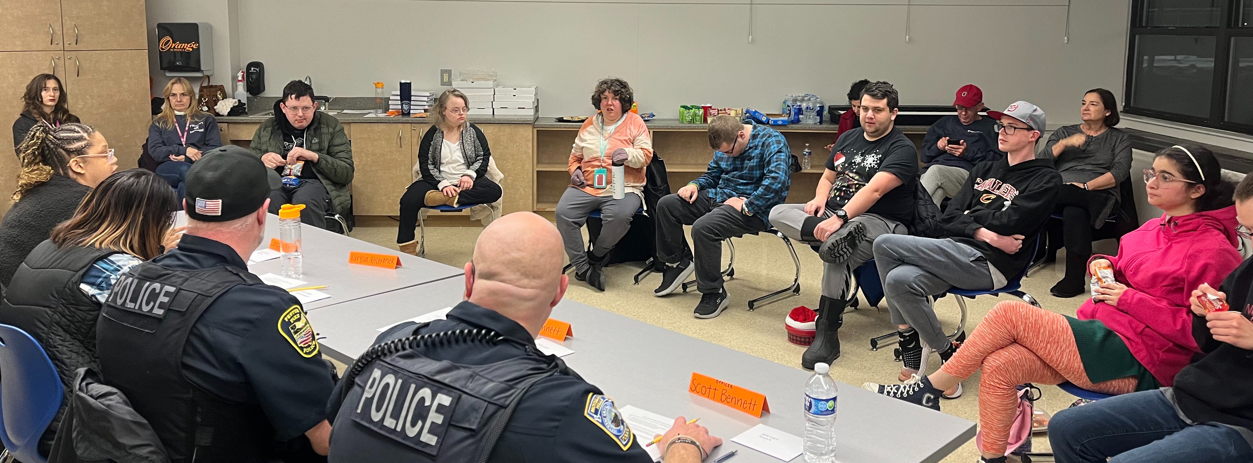 A group of people facing a panel of police officers in a classroom