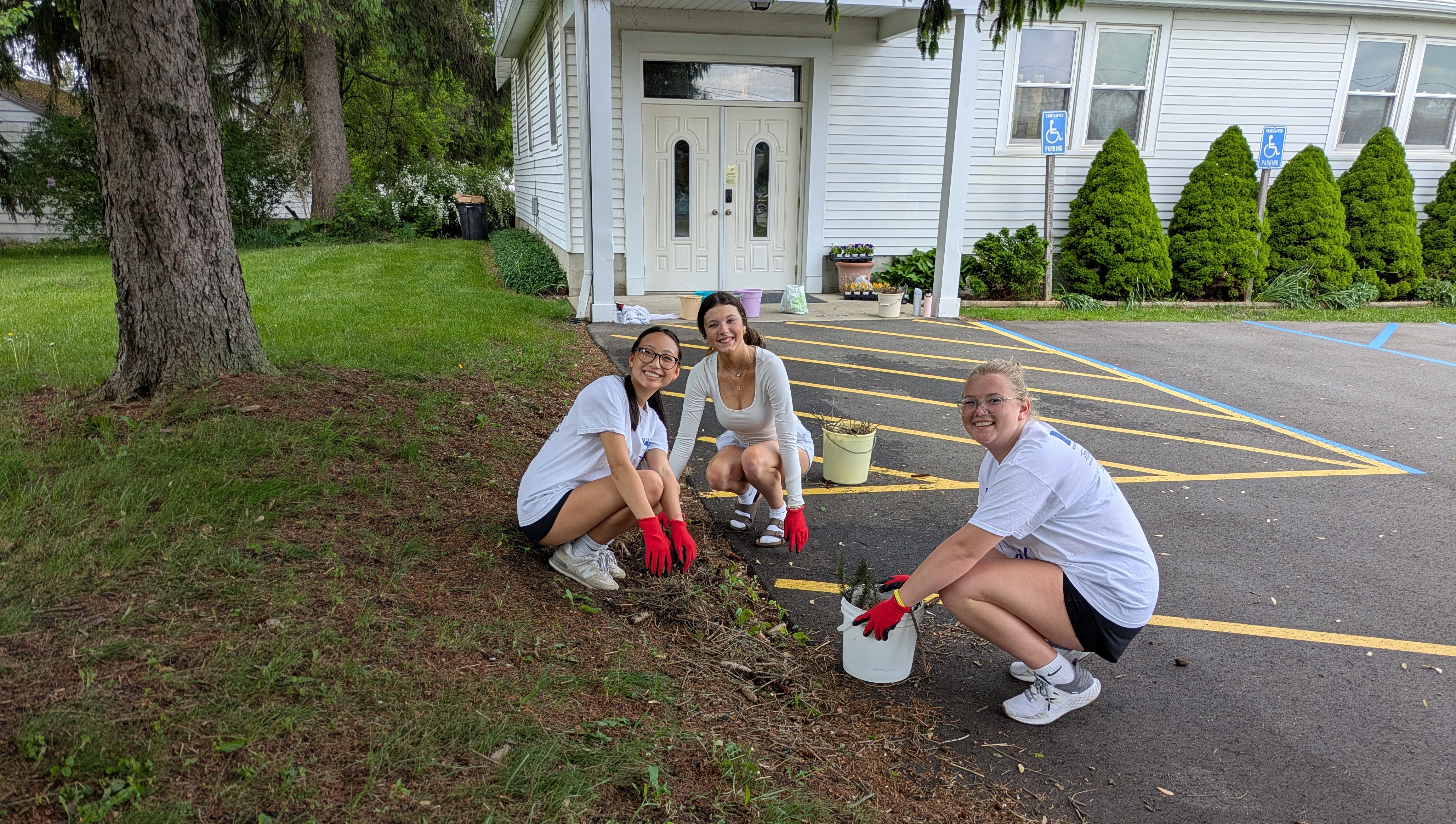 Girls on the ground pulling weeds