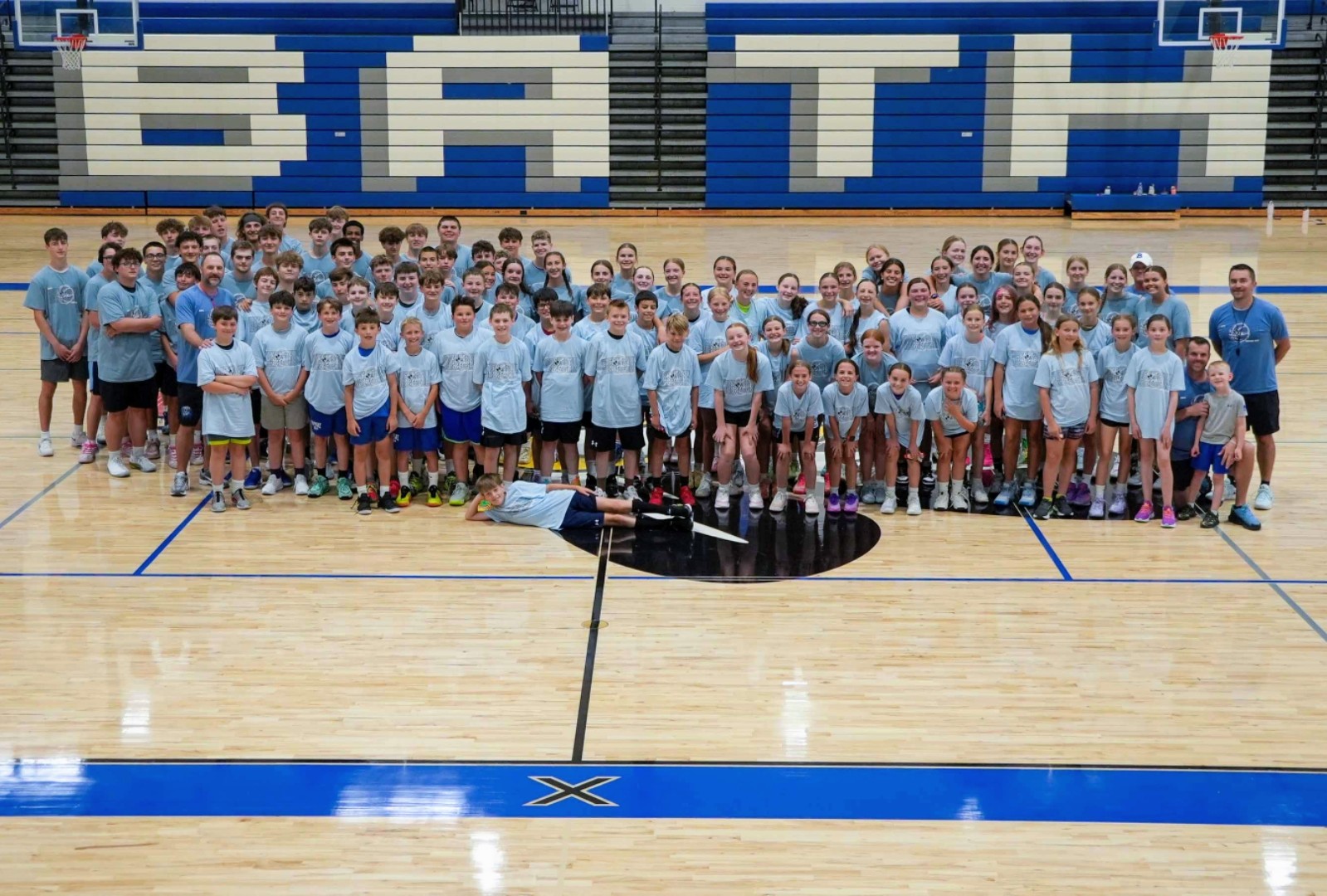 students with basketball camp shirts standing on the court