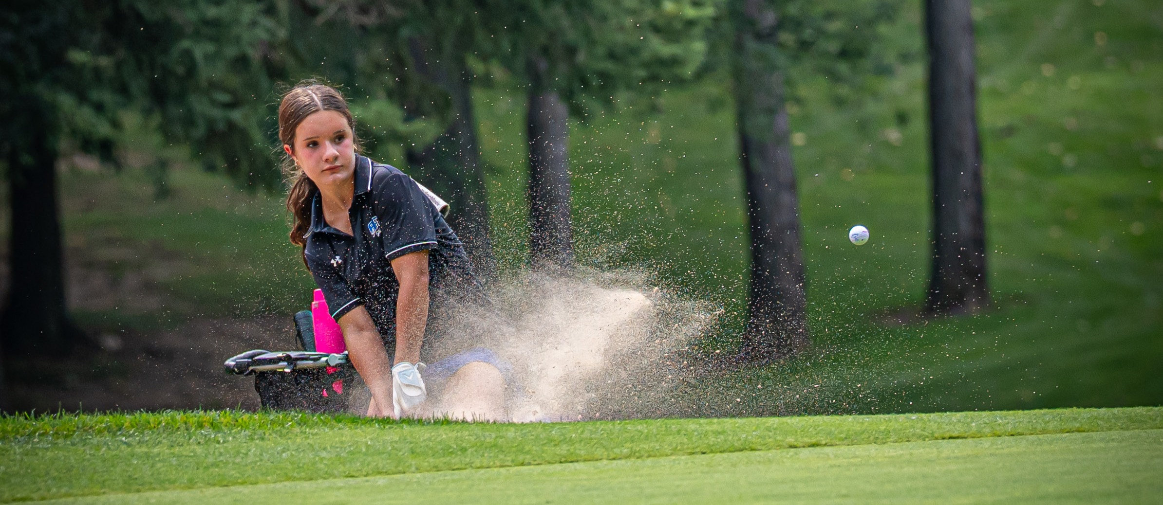 Girl hitting golf ball out of the sand