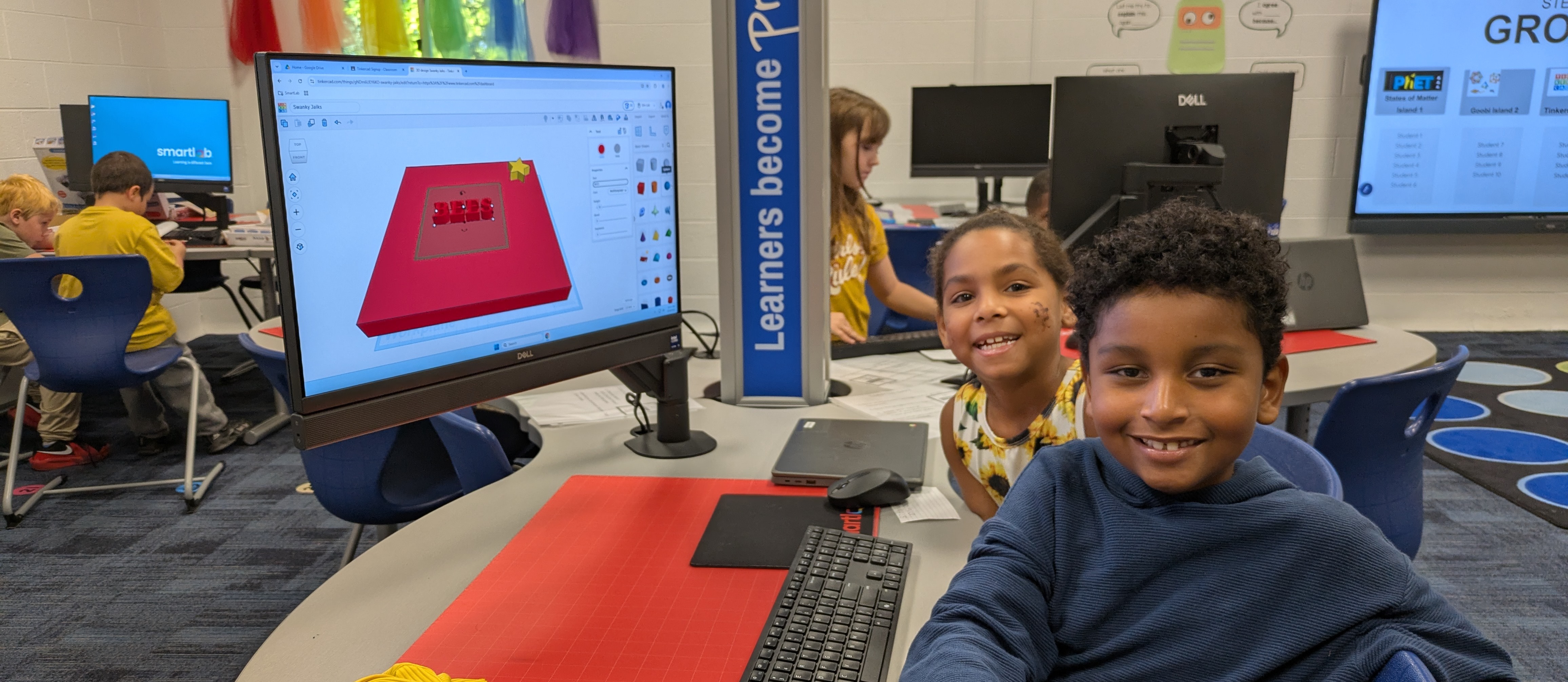 Boy and girls sitting at table with computer desiging a project in tinkercad