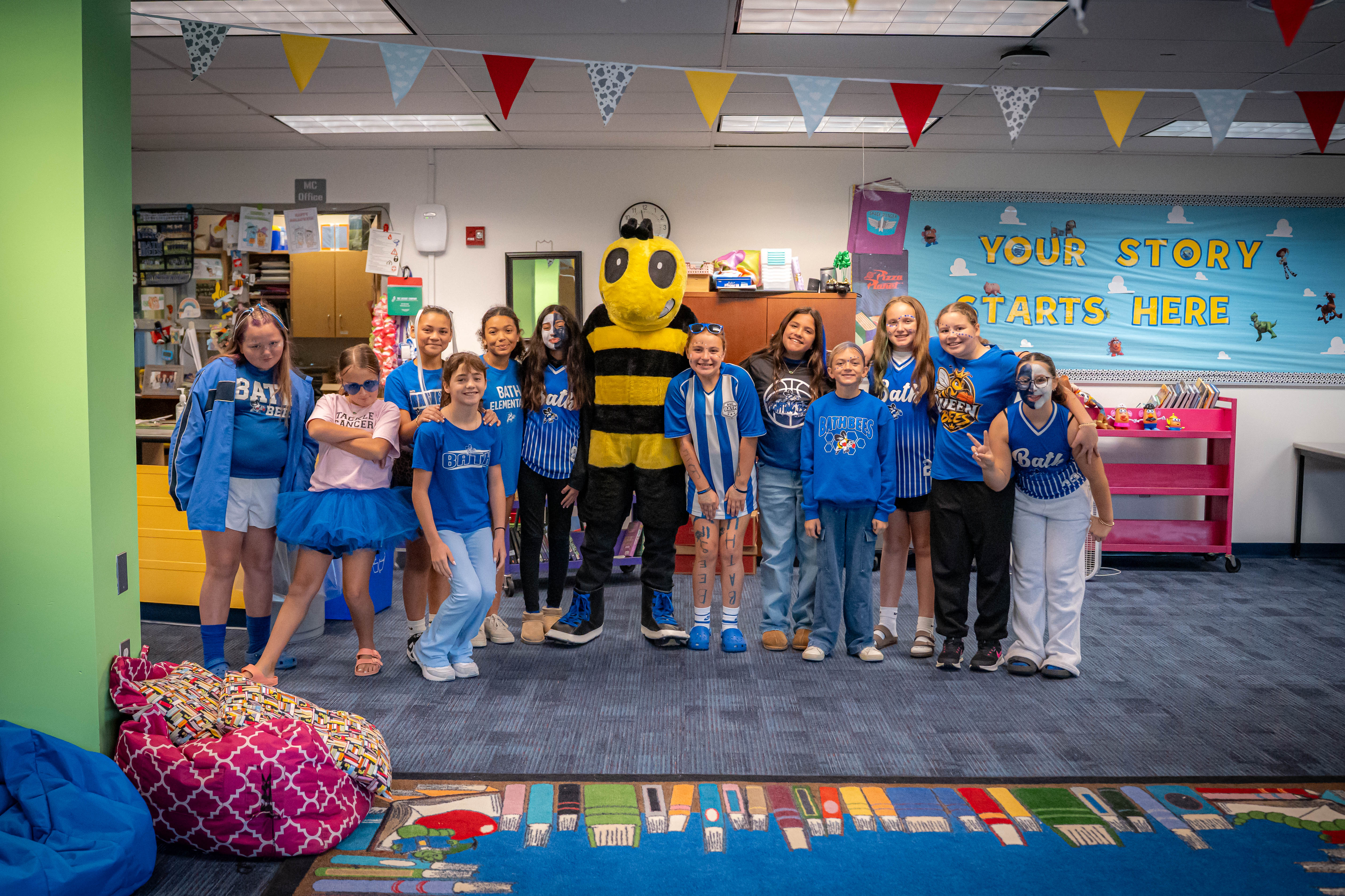 5th grade girls standing with Bee mascot in the library