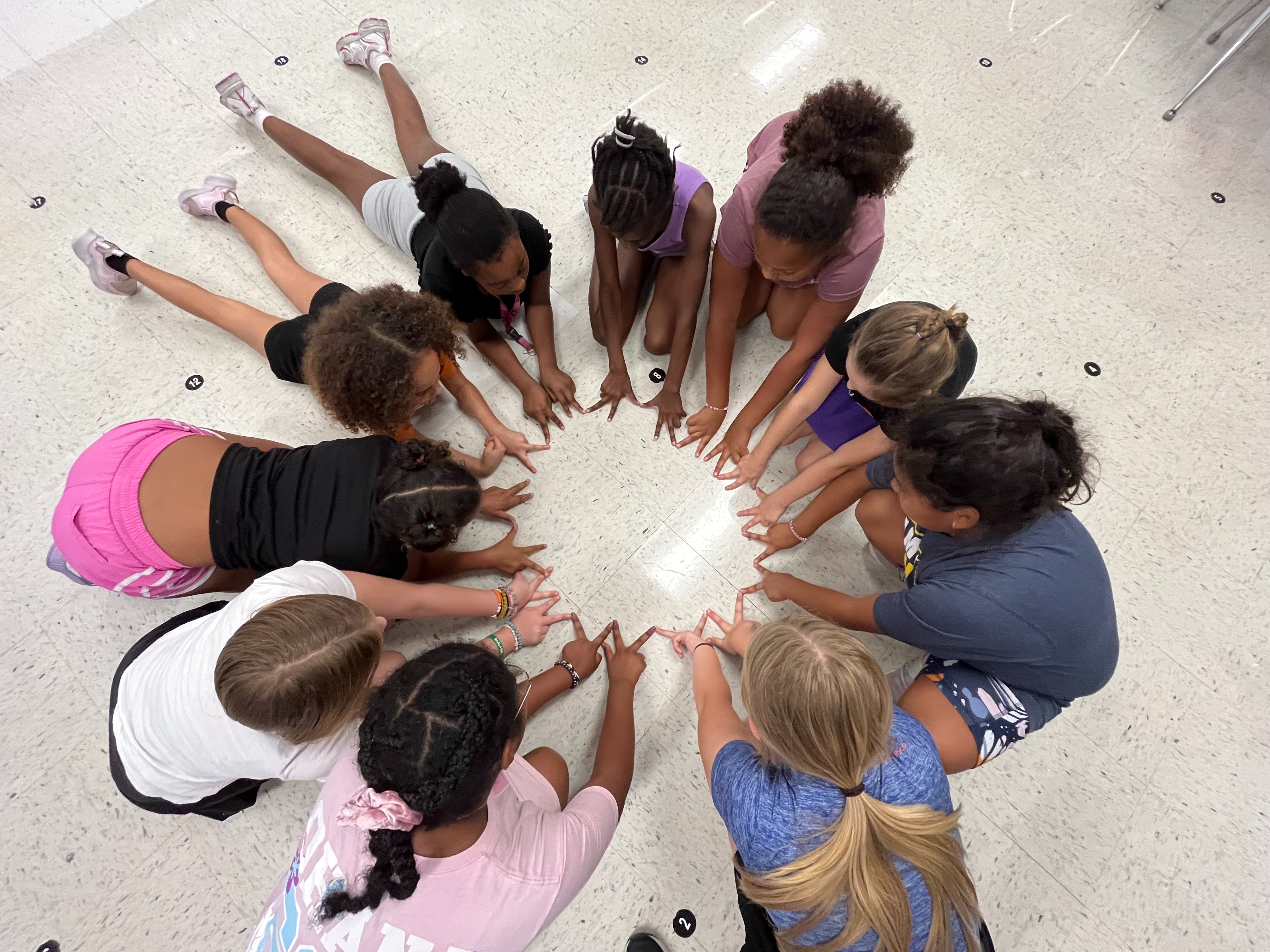 group of girls posing un a circle giving a peace sign