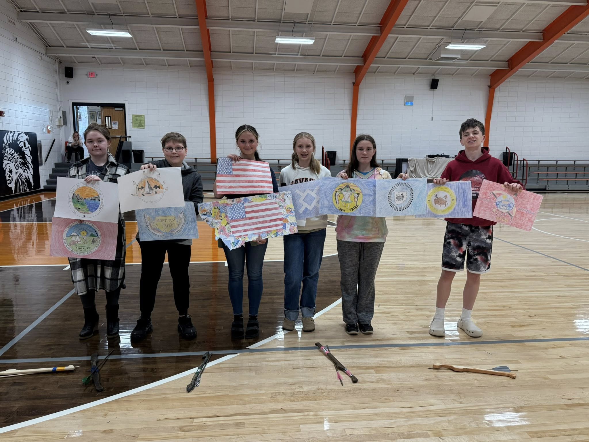 Savage school students holding up drawings, smiling at camera.