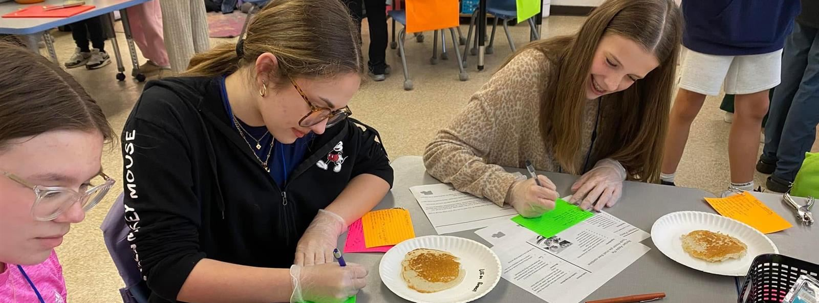 students observe skills on how to make pancakes in culinary club